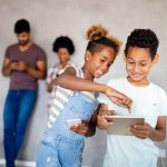 Happy african american family using technical devices, phone. tablet